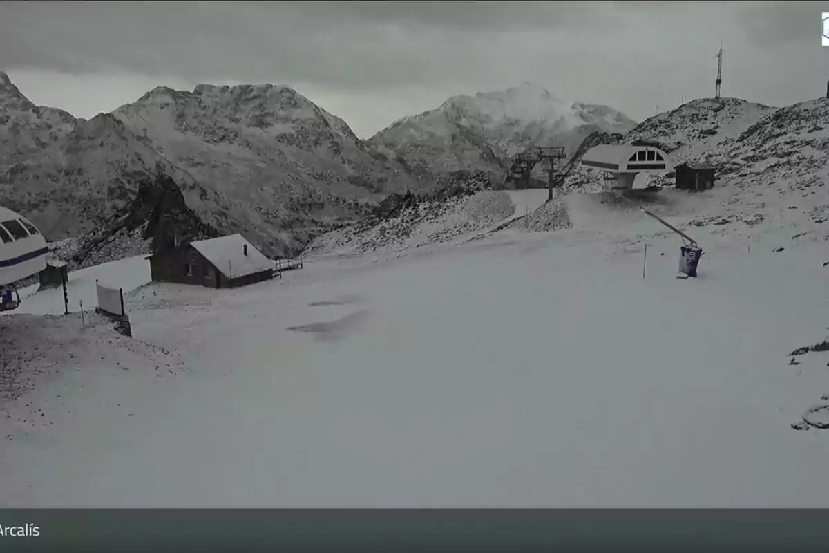 Una estación de esquí cubierta de nieve con montañas al fondo en un día nublado.